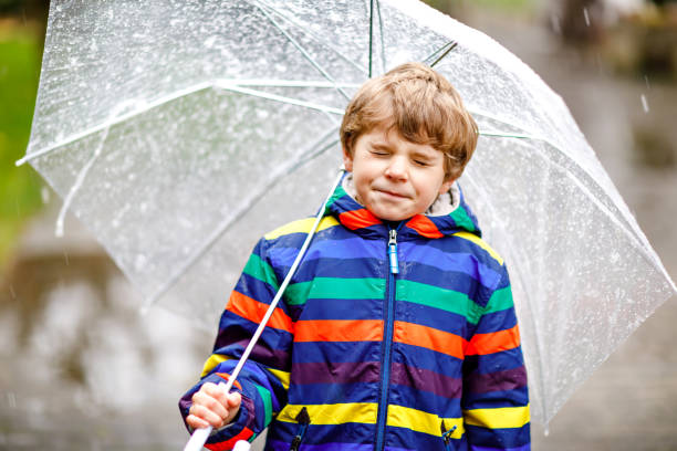 istock Beautiful little kid boy on way to school walking during sleet, rain and snow with an umbrella on cold day. Happy and joyful child in colorful fashion casual clothes. 1183963243