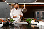 young attractive male cook blows up his protective glove jokes and has fun in the professional kitchen