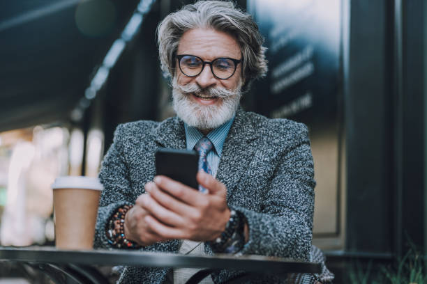 istock Smiling man in glasses is using smartphone 1183974405
