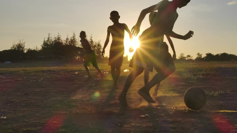 Rural children are playing football at sunset time.slow motion