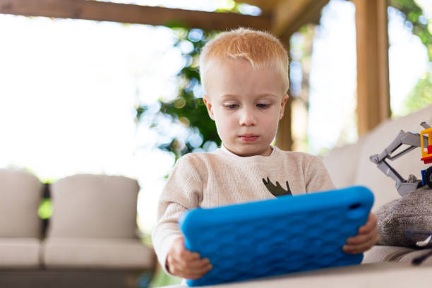 istock Two year old child playing on couch with tablet and toys 1183976555