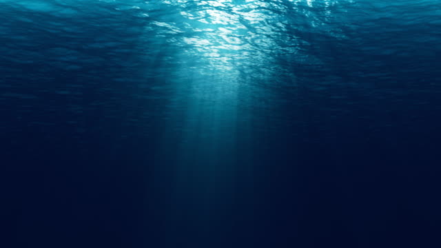 seamless loop of deep blue ocean waves from underwater background, light rays shining through