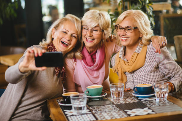 istock Three senior ladies taking selfie with smart phone in cafe 1183979293