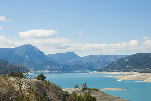 Lake de Serre Poncon Alps de Haute Provence with Chapel Saint Michelle in France. The dam of Serre Ponçon is an embankment dam built between 1955 and 1960 on the Durance river in France and forms the homonymous lake of Serre-Ponçon.