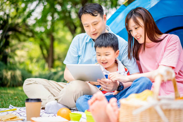 istock Happy family using digital tablet in the park 1183979500