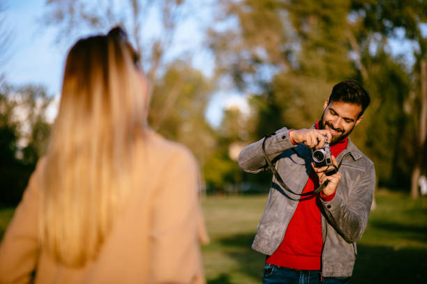istock Young man taking a photo of his girlfriend in a park using camera 1183979600