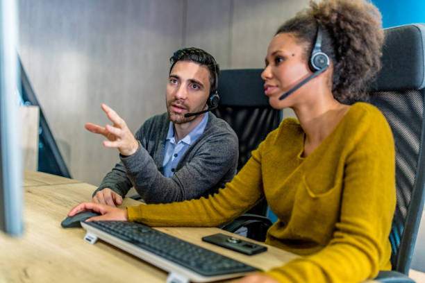 istock Call centre employee helping his colleague 1183979675