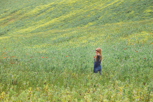 Young woman standing in the field of wild flowers
