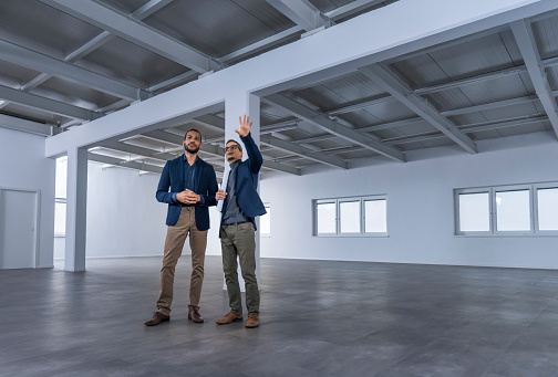 Businessmen discussing with each other in unfurnished office.