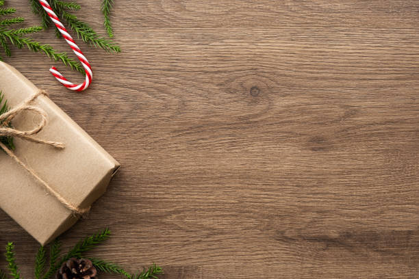 istock Wood table with Christmas decoration including giftbox, candy cane, pine branches and pine cones. Merry Christmas and happy new year concept. Top view with copy space, flat lay. 1183983389