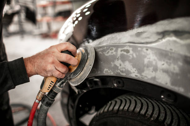 Using a portable electric sander to sand off damaged paint from a car quarter panel Using an electric orbital sander to sand out a filler on a damaged quarter panel. door panel stock pictures, royalty-free photos & images