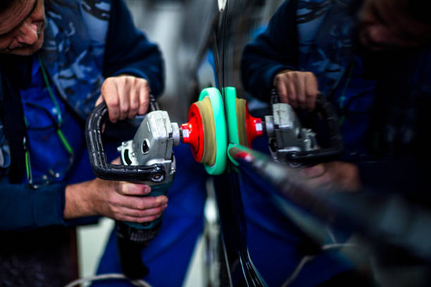 Polishing a car part with a portable handheld polisher in a car paint shop Technician polishing a car segment using an electric orbital polisher. door panel stock pictures, royalty-free photos & images