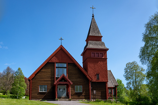Beautiful red timbered church on the countryside in Sweden on a beautiful summer day with clear blue sky and sunlight