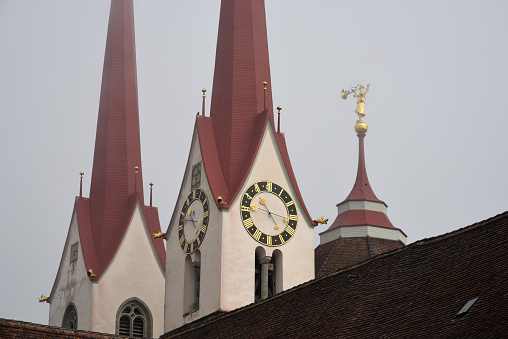 Close-up of a Church Tower (Muri AG) with its clock. The Image was captured during autumn season at a foggy day.swi