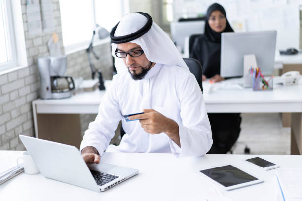 istock Arab businessman using credit card and laptop in modern workplace 1183992258