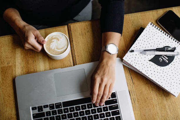 istock Young business woman sitting at table and taking notes in notebook.On table is laptop, smartphone and cup of coffee. Blogger 1183992340