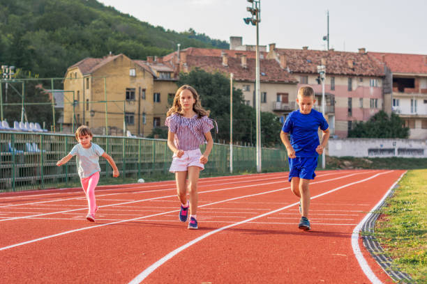 istock Three young kids running on outdoor track. 1183994033