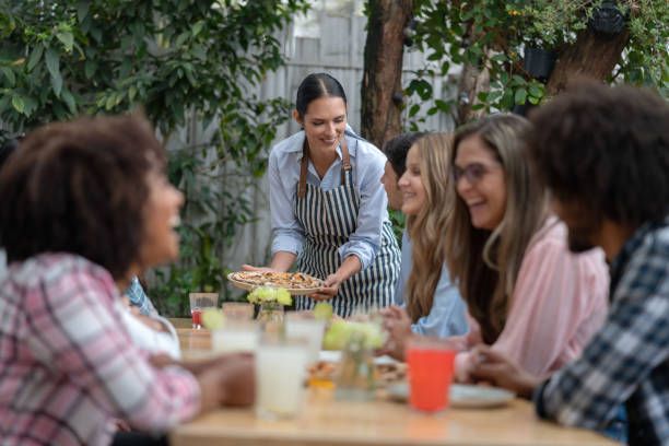istock Waitress serving pizza to a group of people at a restaurant 1183994178