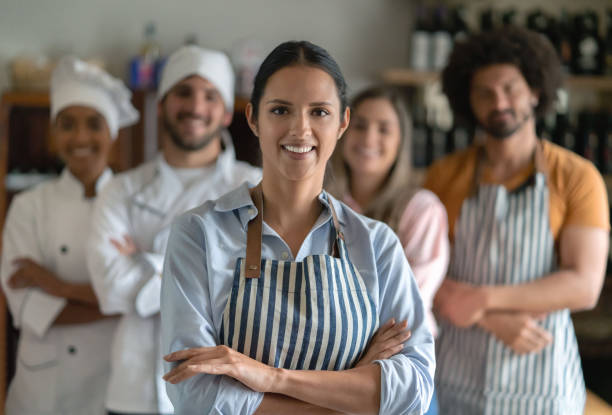 istock Happy waitress working at a restaurant with the staff at the background 1183994218