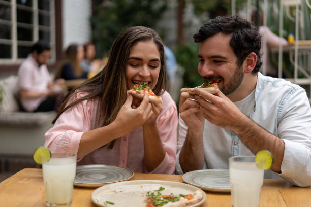 istock Happy couple eating pizza at a restaurant 1183994237
