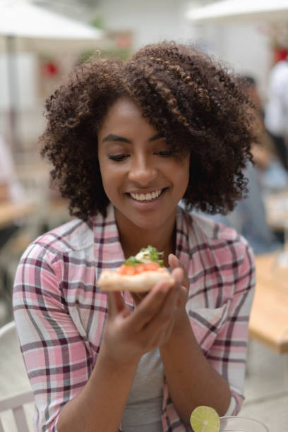 istock Happy woman eating pizza at a restaurant 1183994244