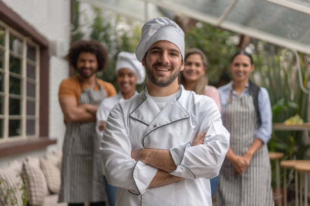 istock Happy chef at a restaurant with a group of workers 1183995680