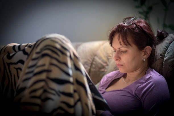 Close up color image depicting a caucasian woman in her 30s reading a hardcover book in a cosy setting at home. Plenty of room for copy space.