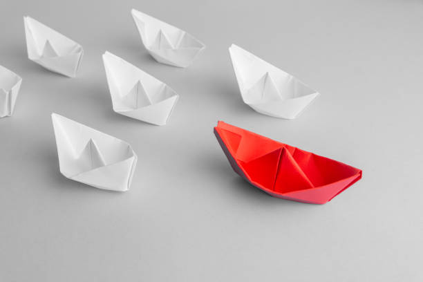 istock Leadership concept using red paper ship among white. From above. text space 1183996792