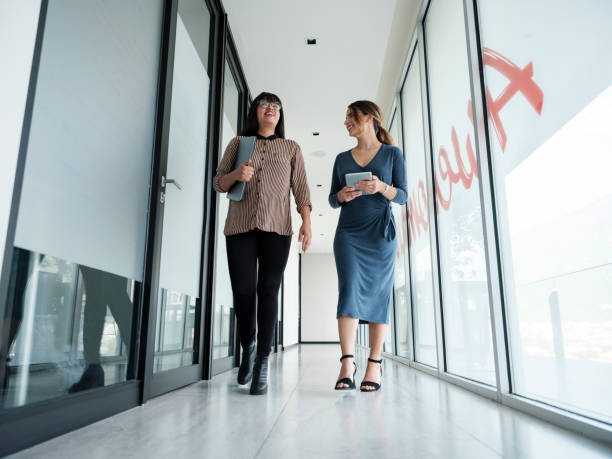 istock Two latin busineswomen walking in corridor at work 1183996973