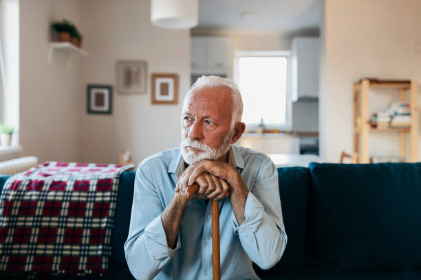 älterer mann sitzt allein zu hause - men senior adult serious depression stock-fotos und bilder