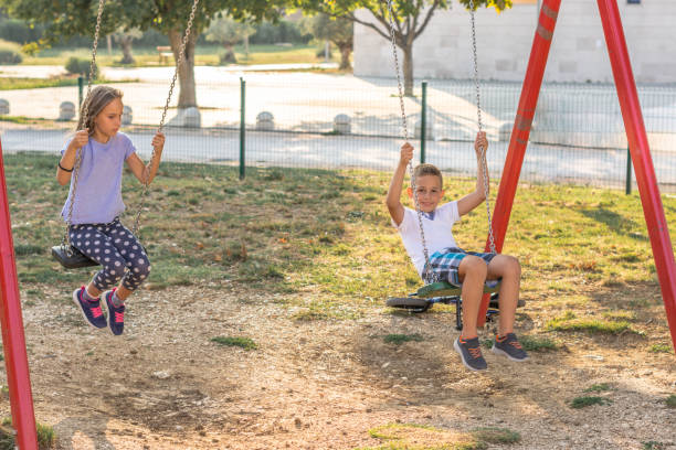 istock Two kids swinging in the park. 1183998128