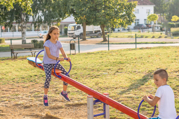 istock Siblings playing on seesaw at park during sunny day. 1183998449