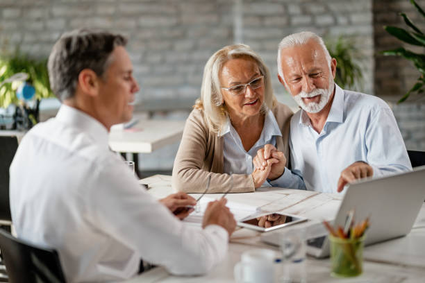 istock happy senior couple using computer while having a meeting with real estate agent. 1183999709
