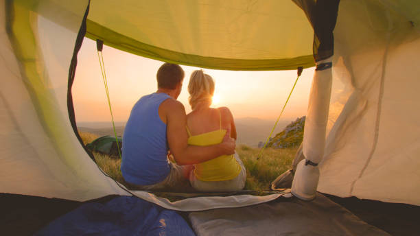istock CLOSE UP: Couple cuddling and watching sunset together during hiking adventure. 1184000182