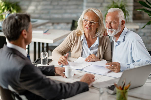 istock Happy senior couple going through blueprints while talking with real estate agent. 1184000406