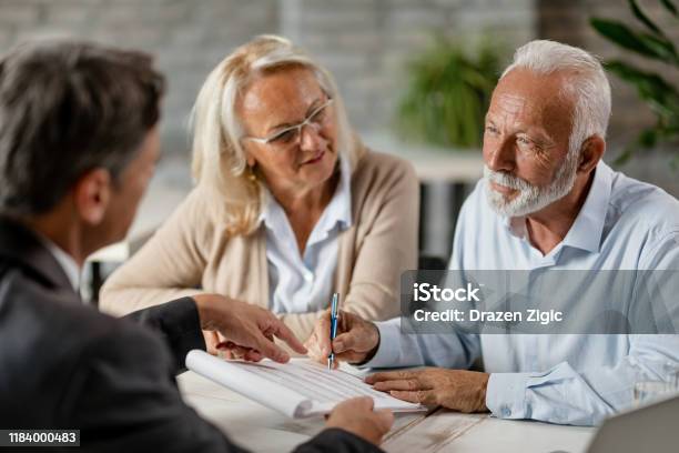 Senior Couple Signing A Contract While Having A Meeting With Insurance Agent In The Office Stock Photo - Download Image Now