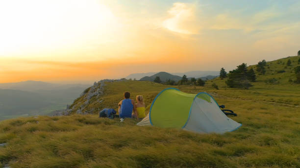 istock AERIAL: Active young couple sitting by their tent and watching the sunset. 1184000489