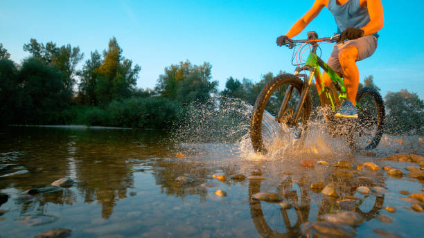 istock LOW ANGLE: Active man riding his mountain bike and splashing refreshing water. 1184000643