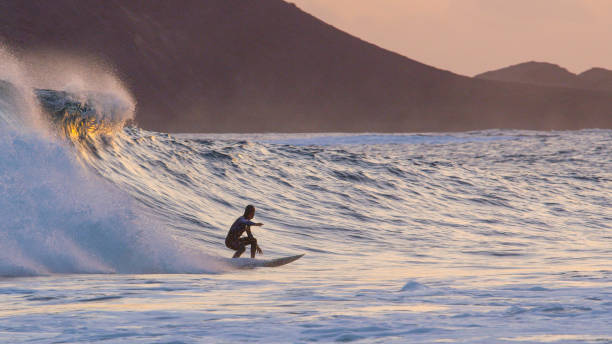 istock Athletic surfer dude carving large breaking wave at colorful summer sunset. 1184002213