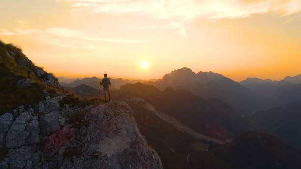 istock DRONE: Flying around a male hiker standing on the mountain peak at sunset. 1184002264