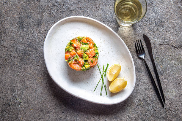 istock PERUVIAN FOOD. Salmon ceviche with avocado, spring onion and lemon on white plate served with white wine 1184002628