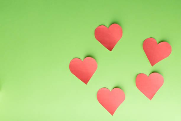 istock Five paper hearts on a green background. 1184002700
