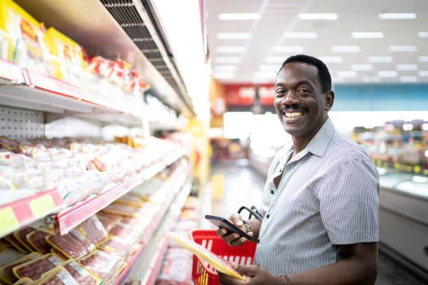 istock Portrait of man looking at camera and using phone in supermarket 1184002821