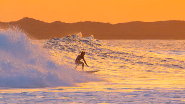 istock Surfer dude crouches on his surfboard while surfing a beautiful breaking wave 1184003411