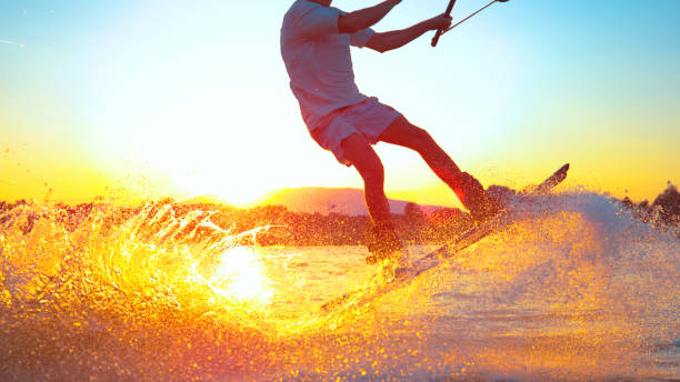 sun flare: cool серфер чувак делает 180 олли в то время как вейкбординг на солнечный вечер - wakeboarding waterskiing water ski sunset стоковые фото и изображения