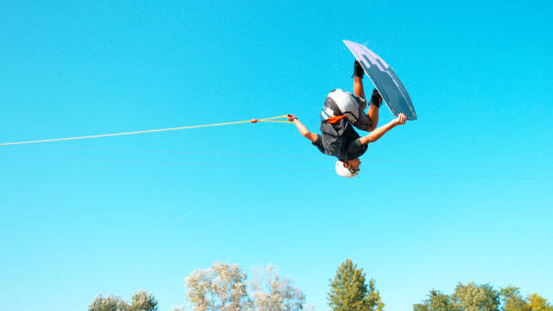 Wakesurfer does a spinning barrel roll while riding around the scenic lake.