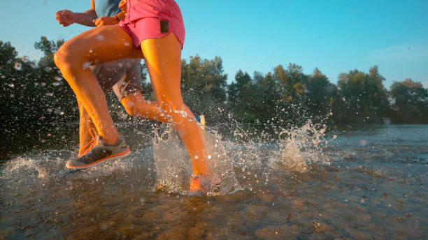istock CLOSE UP: Fit couple running through idyllic forest and in the shallow stream. 1184004307