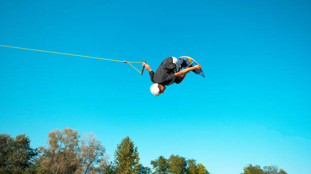 istock Athletic man does a cool spinning backflip while wakesurfing at the cable park. 1184004835