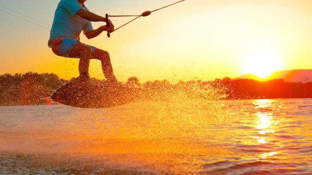 �クローズアップ:クールなウェイクボーダーは、湖を横切ってスピードを出しながら180オリーを行います。 - wakeboarding waterskiing water ski sunset ストックフォトと画像