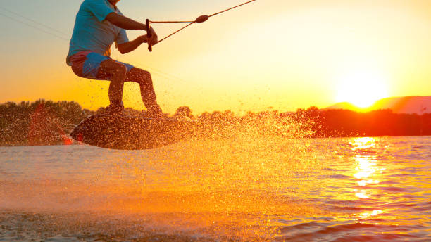 istock CLOSE UP: Cool wakeboarder does a 180 ollie while speeding across the lake. 1184004898